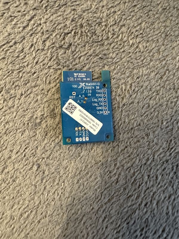 Electronic module board with pin labels on a gray surface.