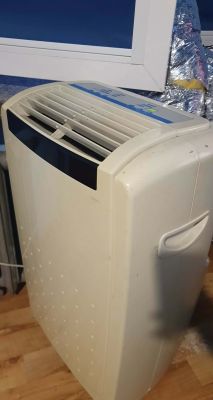 Portable air conditioner by an open window with a white frame and a connected silver exhaust hose