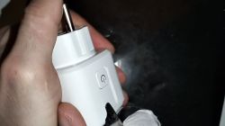 A person holds a white smart plug with a socket, featuring a side power button.