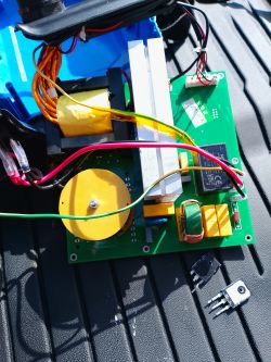 Open device housing with green PCB, wires, heatsink, and power parts; two MOSFET-like TO-220 parts nearby