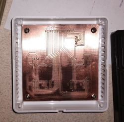 Płyta PCB z wzorem ścieżek zamocowana w plastikowej obudowie.
