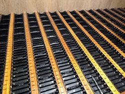 Energy storage battery pack with connected cells Rows of black battery cells connected with copper busbars, arranged on a wooden background.