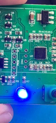 Printed Circuit Board with Blue LED Close-up of a green printed circuit board with electronic components and a lit blue LED.