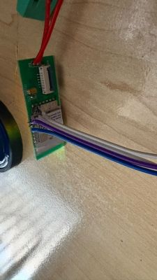 Small PCB with a shielded module and connected wires on a wooden surface