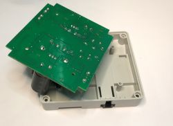 Płytka drukowana z elementami elektronicznymi znajduje się na plastikowej obudowie.