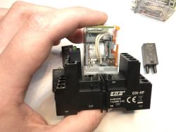 Przekaźnik elektromagnetyczny GN-4P trzymany w dłoni, widoczna cewka i styki