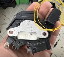 Moduł regulatora napięcia do alternatora w ręce osoby, z zaznaczoną częścią żółtym kółkiem.