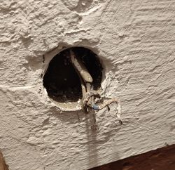Wystające kable elektryczne z otworu w ścianie.