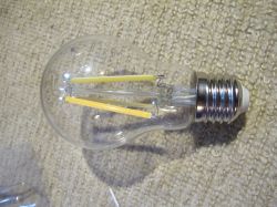 LED light bulb with transparent glass lying on a carpet.
