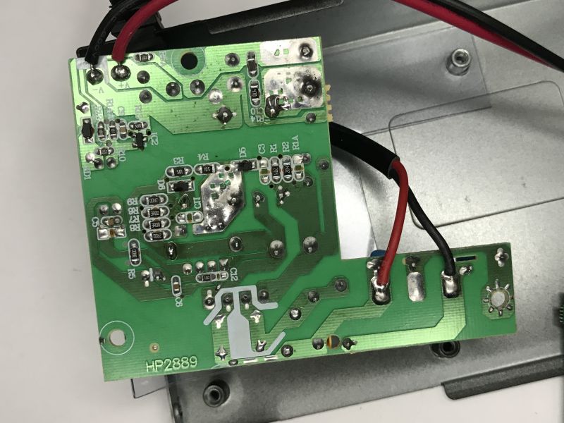 Underside of a green PCB with red and black wires soldered, mounted inside a metal enclosure