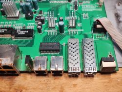 Fragment płyty głównej starego switcha z widocznymi portami RJ45 i SFP, pokrytymi śladami korozji.