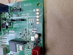 Fragment zielonej płytki PCB z nadrukami „RADIO” i „CONNECTIVITY MODULE” oraz złączami i elementami SMD