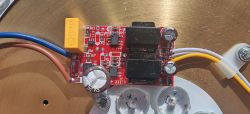 Płytka sterownika LED na czerwonym PCB z kondensatorami i przewodami podłączonymi z lewej i prawej strony