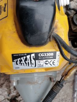 Zbliżenie na silnik spalinowej podkaszarki Texas CG330B z widoczną tabliczką znamionową.