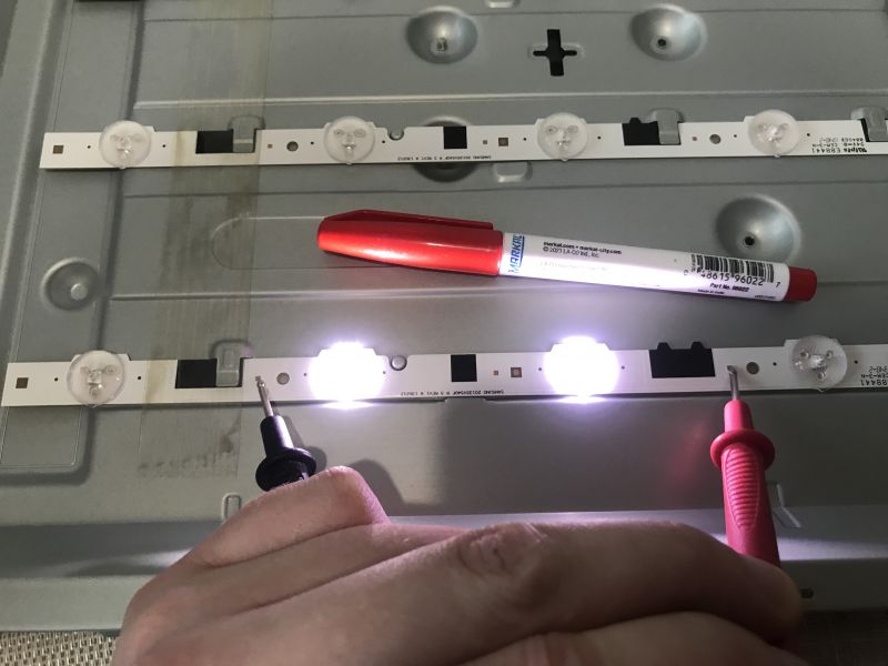 Testing LED Strips in Television Two LED strips, with one being tested using power supply probes.