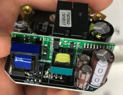 Close-up of a switch interior: green PCB with electrolytic capacitors and black relays, held in a hand
