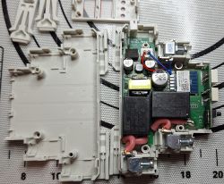 Disassembled electronic module with PCB, relays, and screw terminals visible