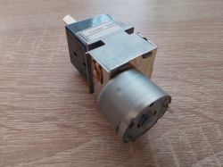 Potencjometr ALPS z silnikiem, model RK271 LOG 50KAX2, widziany z boku na drewnianym tle.