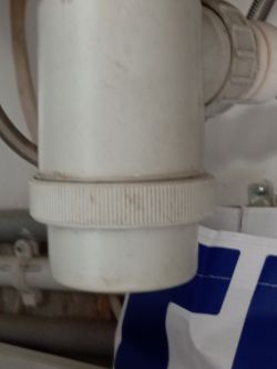Odkręcony syfon z widoczną nakrętką pod zlewem.