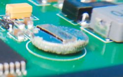 Circuit board with a circular 3V battery covered in white residue.