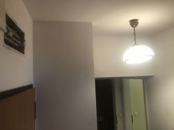 Widok na ścianę z rozdzielnicą i wisząca lampa w korytarzu.