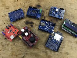 Various prototype boards and electronic modules on a wooden surface.
