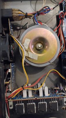 Wnętrze urządzenia elektronicznego z widocznym transformatorem toroidalnym oraz wiązką przewodów.