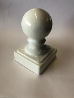 Biała porcelanowa gałka na kwadratowej podstawie.