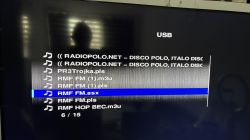 Wyświetlacz telewizora z listą plików audio na podłączonym urządzeniu USB, z zaznaczonym plikiem RMF FM.asx.