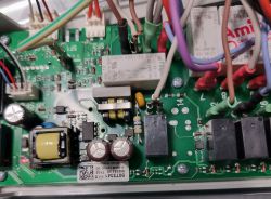 Zbliżenie na moduł sterowania piekarnika z widocznymi kolorowymi przewodami i elementami elektronicznymi.
