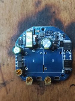Round printed circuit board with electronic components on a wooden surface.