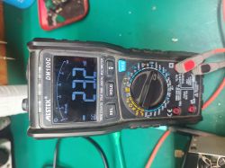 Cyfrowy multimetr Mastech DM100C pokazujący 23,2 mV DC na zielonym blacie