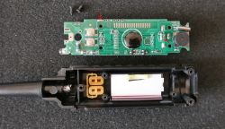 Płytka drukowana z elementami elektronicznymi i częściowo rozebrana obudowa urządzenia.