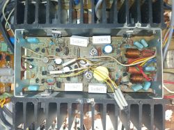 Wnętrze urządzenia elektronicznego z widocznymi elementami, takimi jak kondensatory, rezystory i cewki na płytce drukowanej.