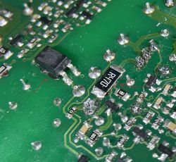 Zbliżenie na płytkę drukowaną z zaznaczonymi elementami elektronicznymi.