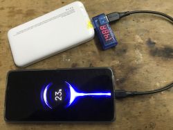 Biały powerbank WPBWE1, woltomierz i smartfon wskazujący ładowanie na poziomie 23%.