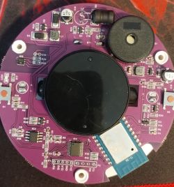 Round purple PCB with SMD parts, a black buzzer/speaker, and a microSD socket with a blue card