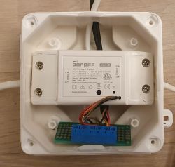 Sonoff Basic with attached circuit board in a white enclosure.