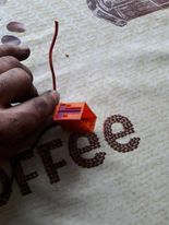 Osoba trzyma pomarańczową kostkę elektryczną z fioletową blokadą.