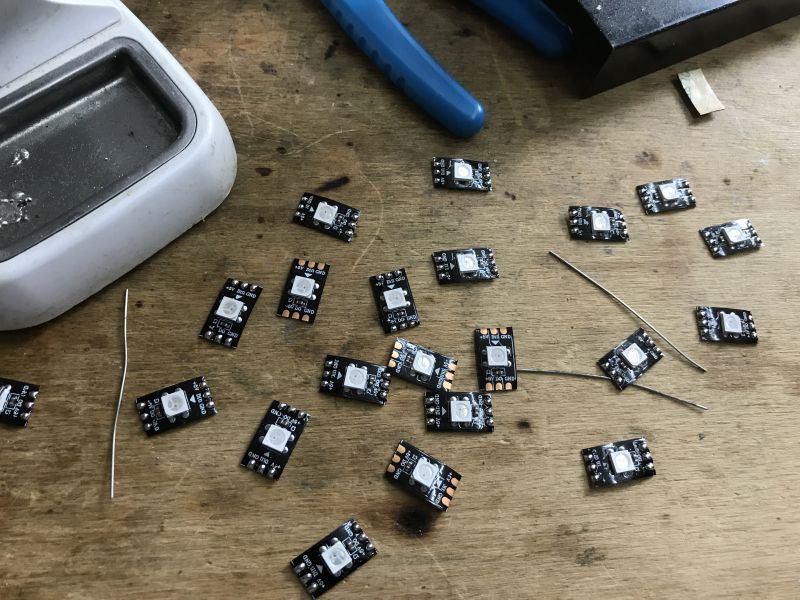 Preparing LED Modules for Assembly LED modules on a workbench beside soldering equipment.