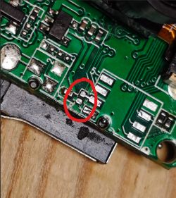 Close-up of a circuit board with a red circle marking a missing surface-mount electronic component.