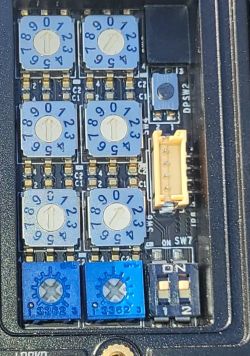 Zbliżenie na płytkę PCB z dziesięcioma przełącznikami obrotowymi i niebieskimi potencjometrami