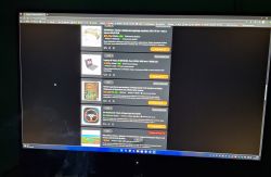 Monitor Gigabyte GS27QA z widocznym podświetleniem wokół dolnych rogów ekranu wyświetlającego ciemną stronę internetową.