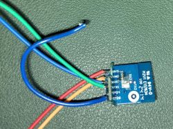 Electronic module with soldered RX/TX wires on a green textured background