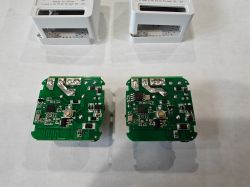 Tuya WiFi Smart Switch Circuit Boards Two green circuit boards of Tuya WiFi Smart Switches against a background of two white enclosures.