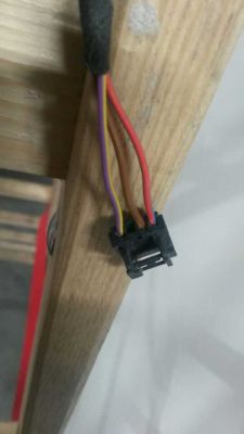 Zbliżenie na złącze z trzema przewodami: fioletowym, brązowym i czerwonym, na tle drewnianej powierzchni.