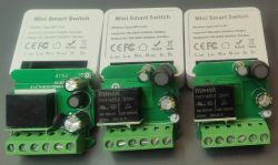 Three mini smart switches with visible circuit boards and electrical components on a table.