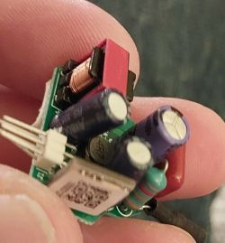 Close-up of a small electronic board with components, held in hand.