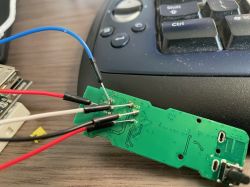 Printed circuit board with attached wires against a keyboard background.