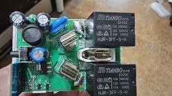 PCB held in a hand with two black TIANBO relays and electronic components